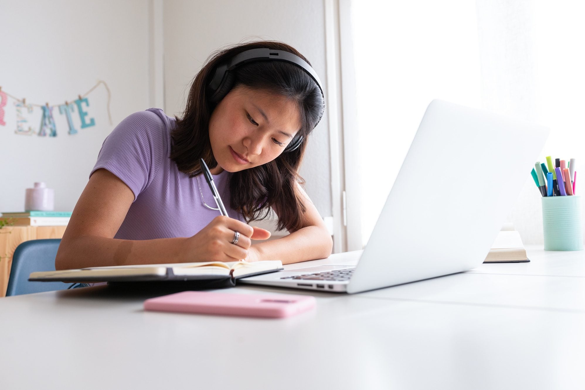 A high school student learning at home with a laptop and notepad