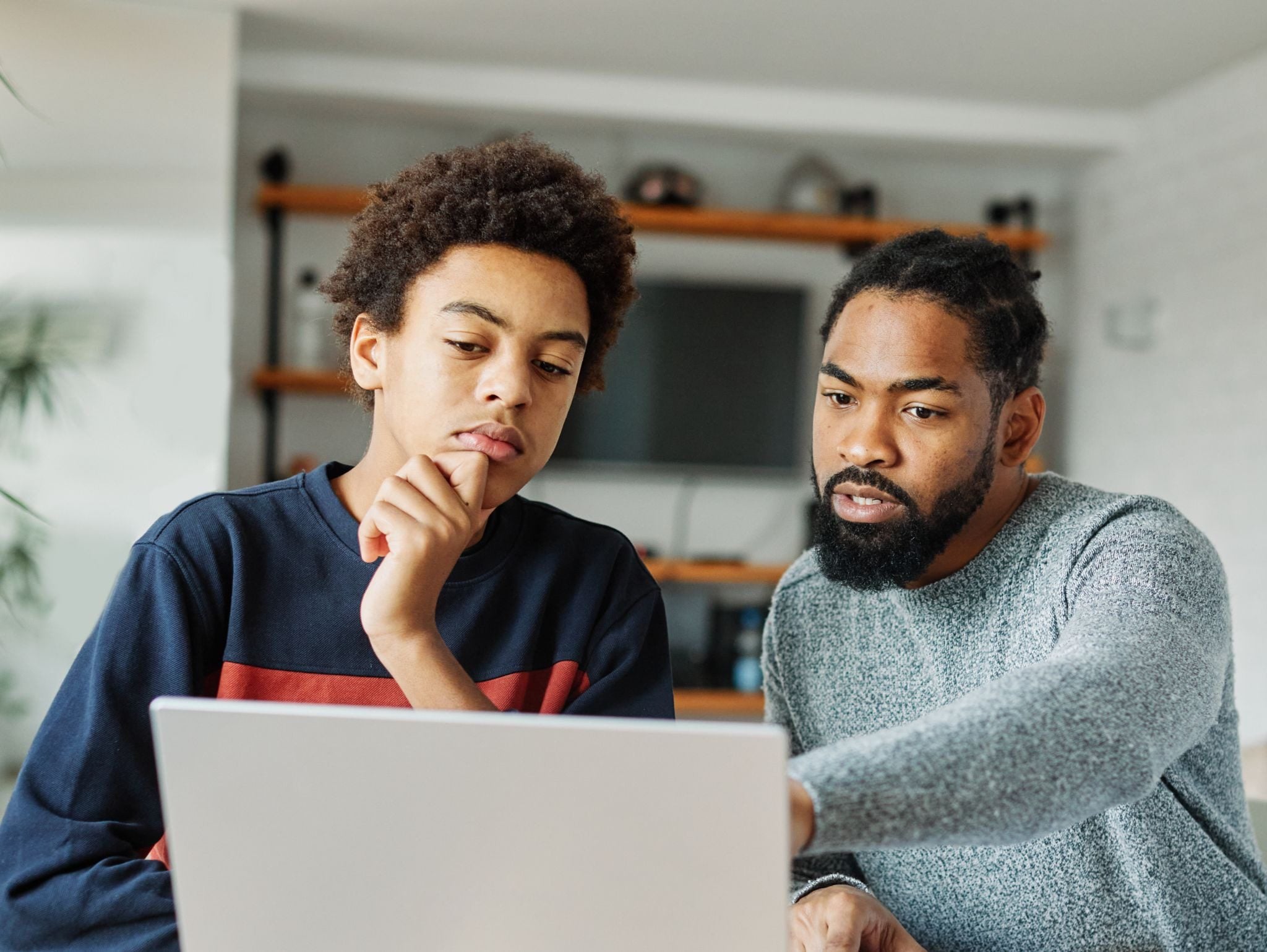 Adult and child looking at a laptop, adult pointing at the screen.