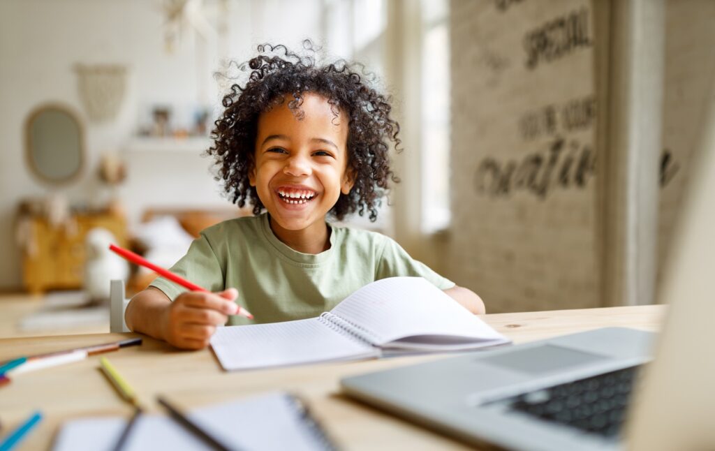 child at organized desk with laptop in a home setting
