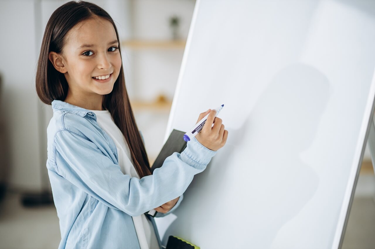 A child about to write something on a whiteboard